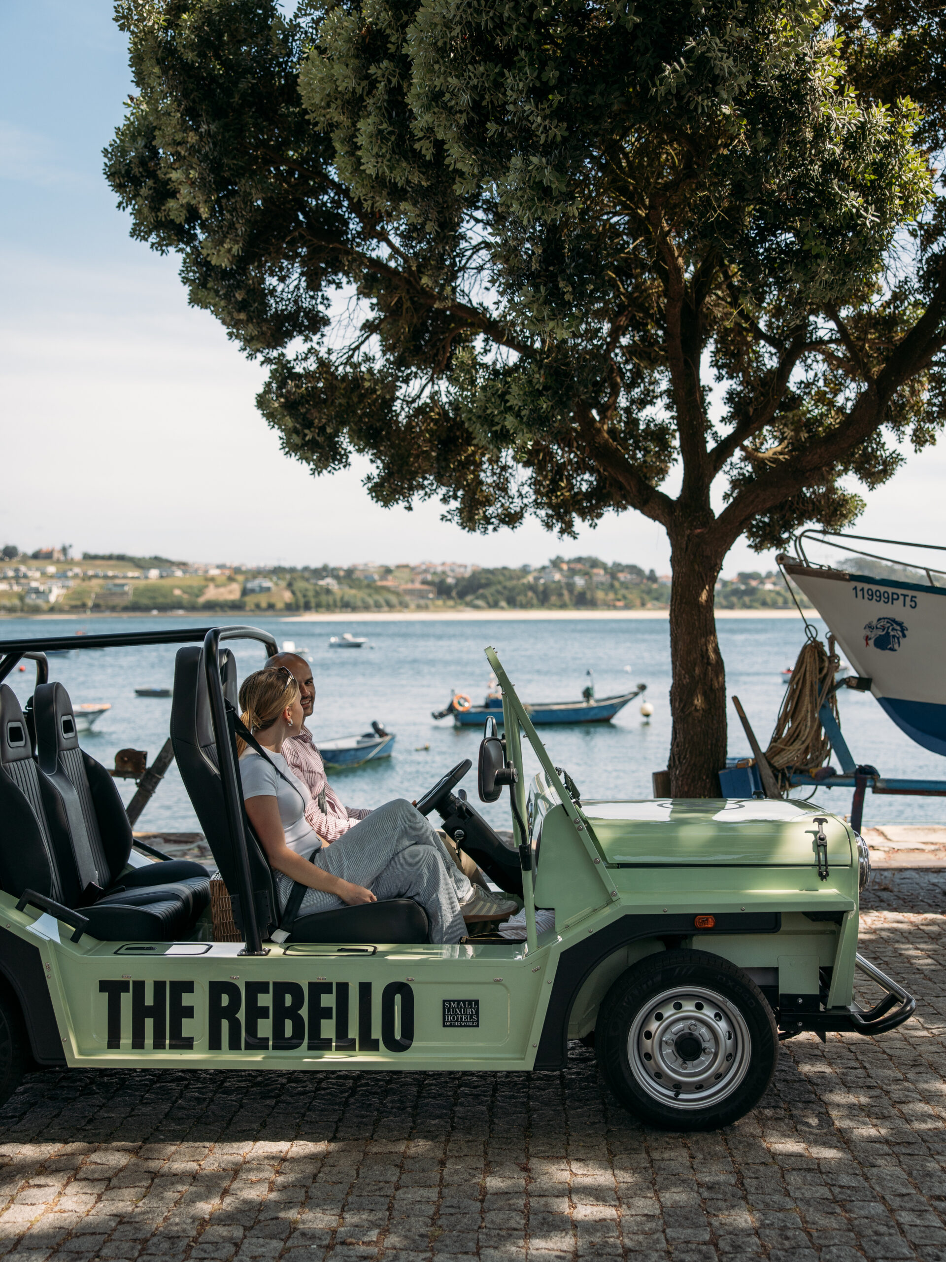 Two women sit in a light green open-top vehicle labeled 